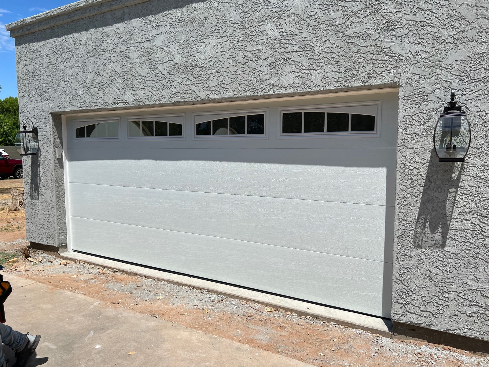 Flush panel garage door with windows on stucco home